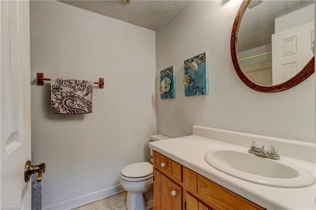 bathroom with vanity, toilet, and a textured ceiling