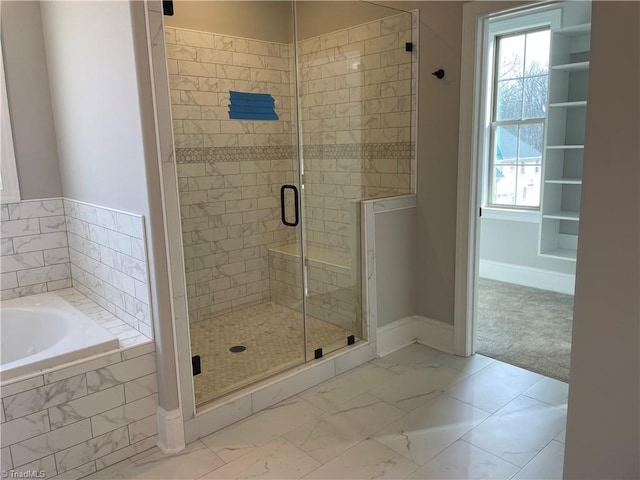 full bathroom with marble finish floor, plenty of natural light, a bath, and a stall shower