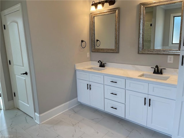 bathroom featuring marble finish floor, a sink, and baseboards