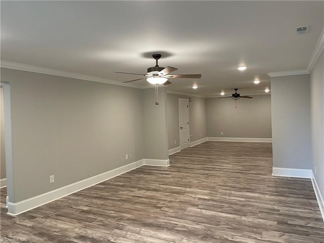 empty room with baseboards, visible vents, dark wood-type flooring, and ornamental molding