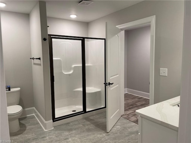 full bath with toilet, visible vents, vanity, baseboards, and a stall shower