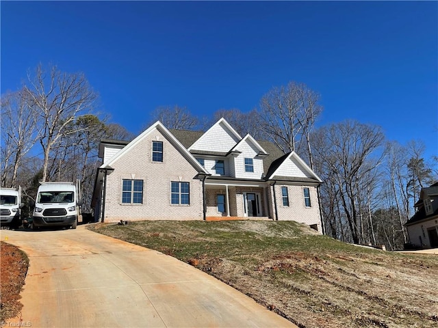 view of front of property with a front lawn, concrete driveway, and brick siding