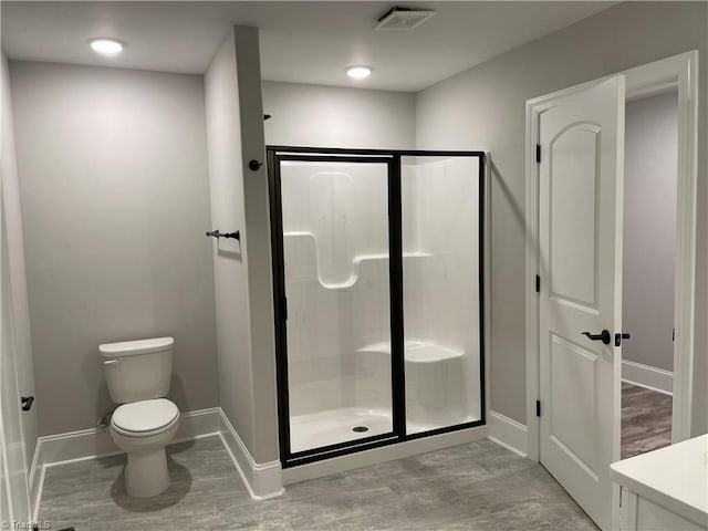 bathroom with toilet, a stall shower, visible vents, and baseboards