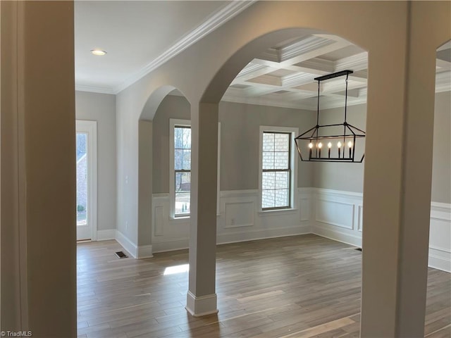 foyer entrance with coffered ceiling, wood finished floors, visible vents, beam ceiling, and crown molding