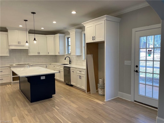 kitchen featuring light countertops, ornamental molding, a sink, light wood-type flooring, and under cabinet range hood