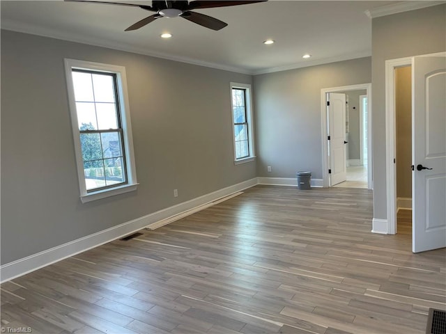 spare room with a healthy amount of sunlight, crown molding, and wood finished floors