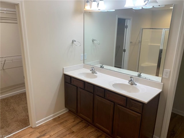 2015 Ram Rd, Greensboro, NC 27405 - bathroom featuring a spacious closet, double vanity, wood finished floors, and an enclosed shower