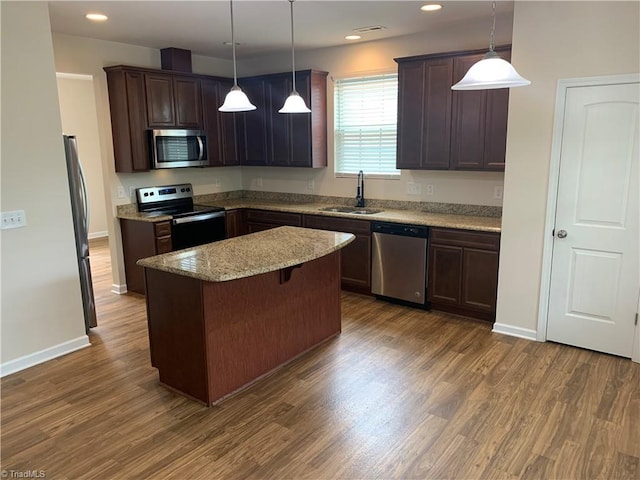 2015 Ram Rd, Greensboro, NC 27405 - kitchen with stainless steel appliances, a center island, dark brown cabinets, dark wood-style flooring, and light stone countertops