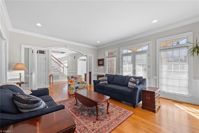 living room featuring crown molding, light hardwood / wood-style flooring, and ornate columns