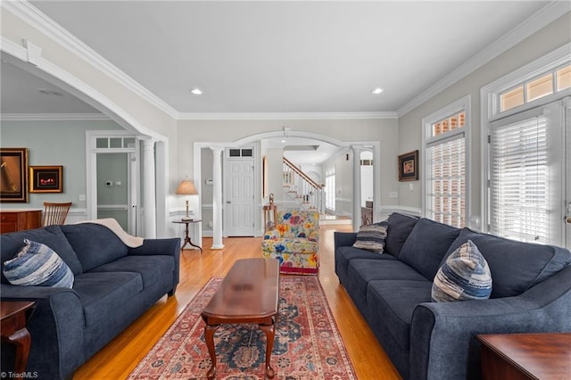 living room featuring ornate columns, ornamental molding, and light wood-type flooring