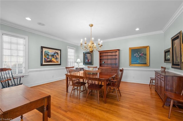 dining room with a notable chandelier, ornamental molding, and light wood-type flooring