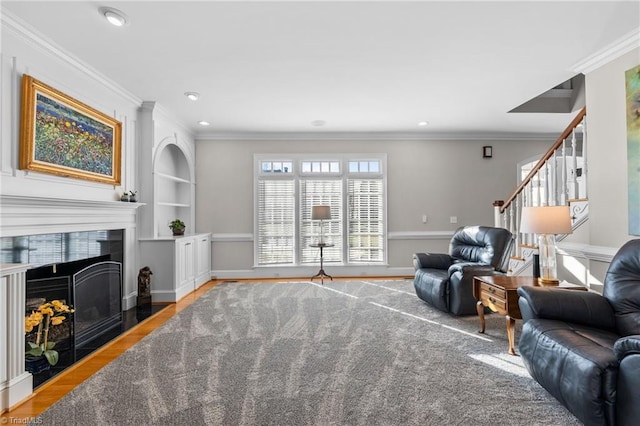 living room with crown molding, a fireplace, hardwood / wood-style floors, and built in features