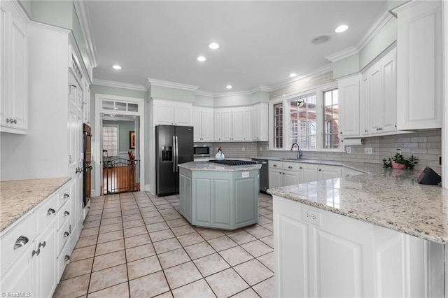 kitchen featuring white cabinetry, appliances with stainless steel finishes, a center island, and light stone counters