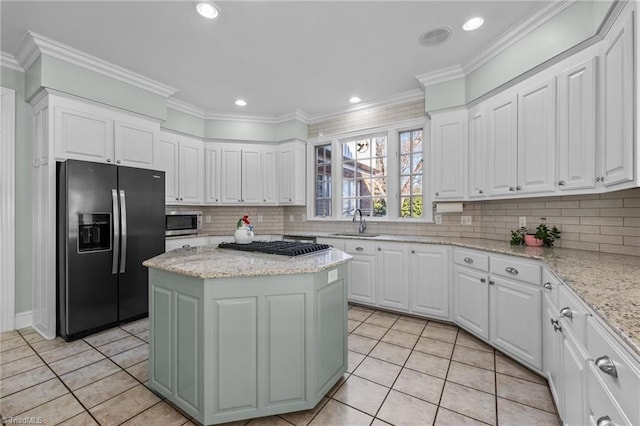 kitchen with white cabinetry, light stone counters, a kitchen island, and appliances with stainless steel finishes