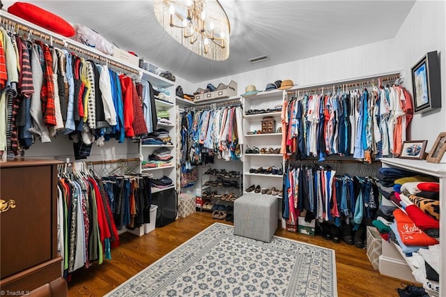 spacious closet with a chandelier and hardwood / wood-style floors