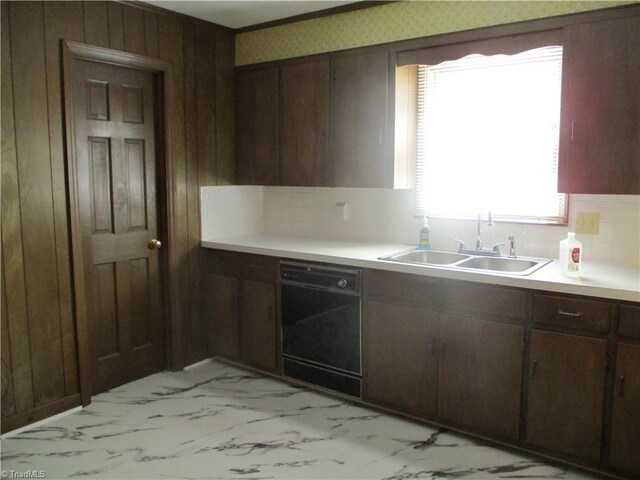 kitchen featuring marble finish floor, dishwasher, light countertops, and a sink