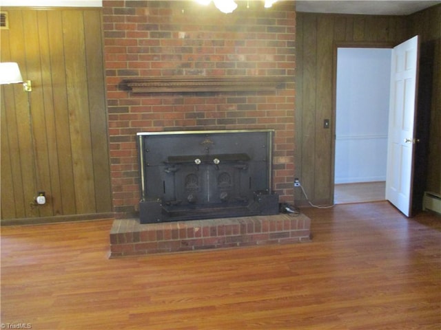 room details with a fireplace, wooden walls, wood finished floors, and baseboards