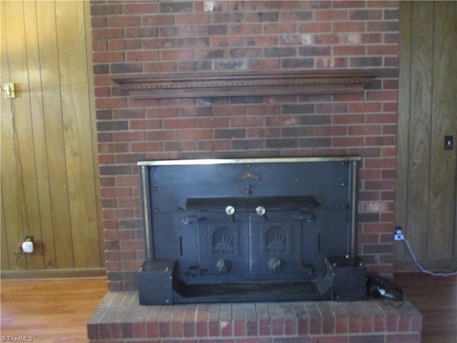 room details featuring wooden walls, wood finished floors, and a fireplace