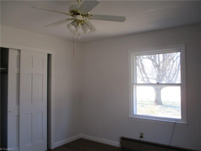unfurnished bedroom with a closet, baseboards, a baseboard heating unit, and a ceiling fan