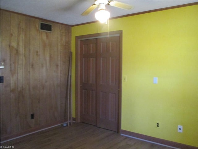 unfurnished bedroom with crown molding, wood finished floors, visible vents, and a closet