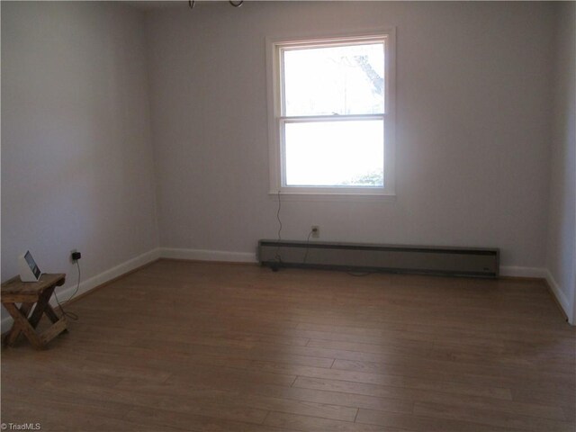 unfurnished room featuring baseboards, a baseboard heating unit, and light wood-style floors