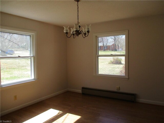 empty room featuring wood finished floors, baseboards, a chandelier, and a baseboard radiator