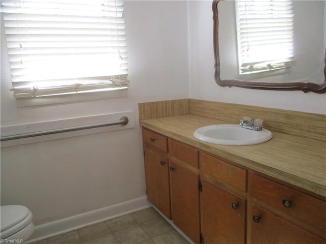 bathroom with baseboards, toilet, and vanity