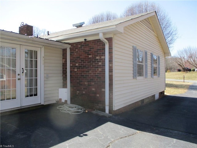 view of side of property featuring brick siding and french doors