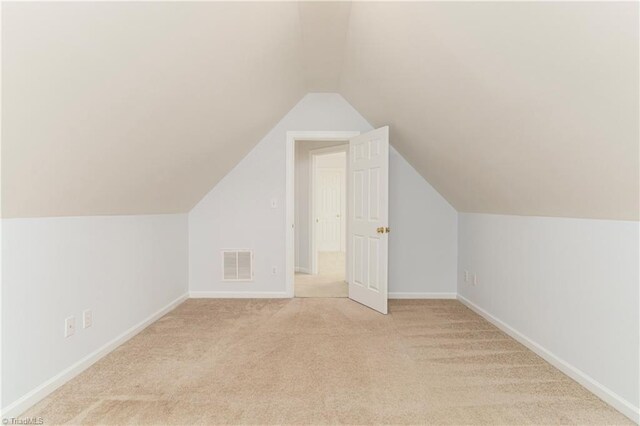 bonus room with light colored carpet and vaulted ceiling