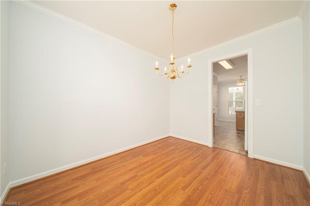 unfurnished room featuring hardwood / wood-style floors, ornamental molding, and a chandelier