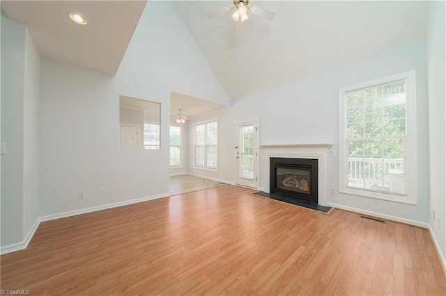 unfurnished living room with high vaulted ceiling, ceiling fan, and light wood-type flooring