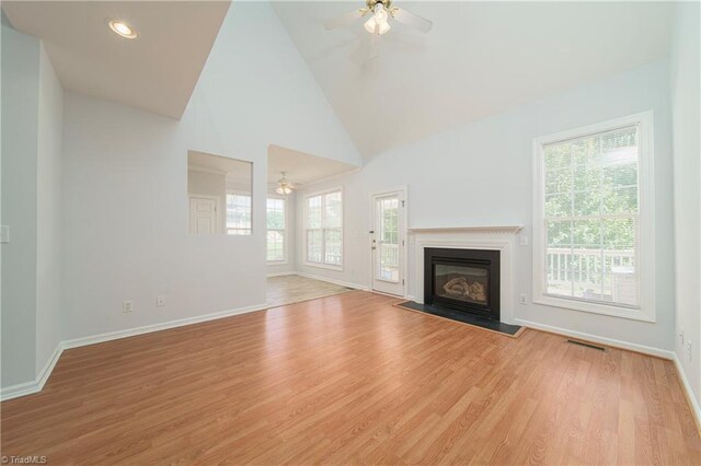 unfurnished living room featuring washer / dryer, ceiling fan, light hardwood / wood-style floors, and high vaulted ceiling