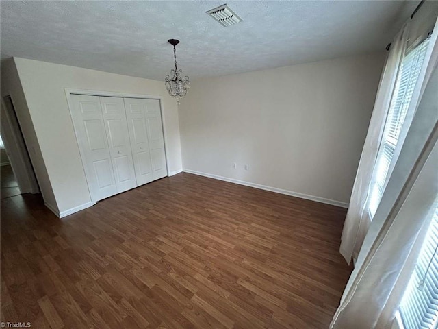 267 S Boyles St, Pilot Mountain, NC 27041 - unfurnished bedroom with dark wood-style flooring, multiple windows, a chandelier, baseboards, and a textured ceiling