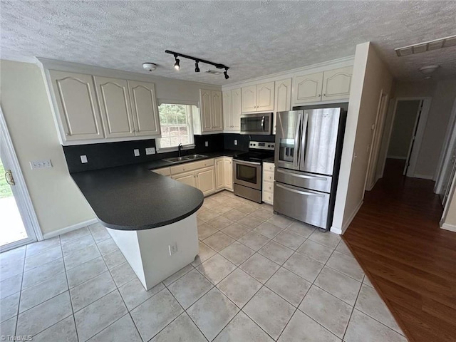 267 S Boyles St, Pilot Mountain, NC 27041 - kitchen with stainless steel appliances, dark countertops, a peninsula, a sink, and light tile patterned floors
