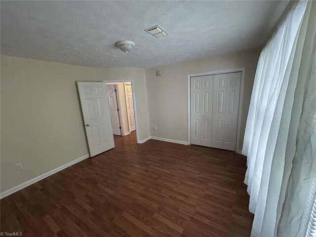267 S Boyles St, Pilot Mountain, NC 27041 - unfurnished bedroom with dark wood finished floors, a textured ceiling, baseboards, and a closet