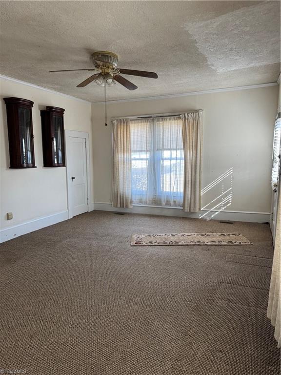 empty room featuring baseboards, carpet floors, a textured ceiling, and a ceiling fan