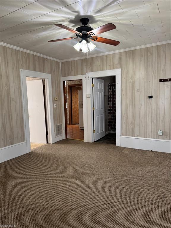 spare room featuring visible vents, a ceiling fan, crown molding, and carpet