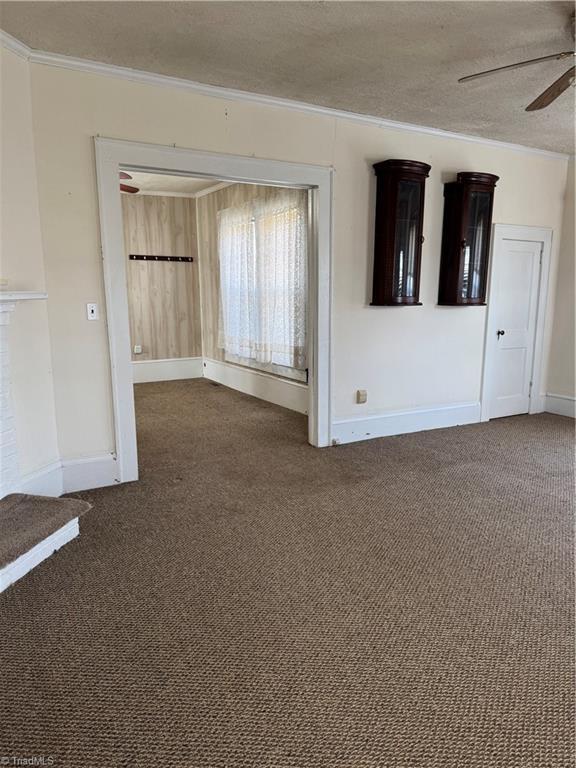 empty room featuring ornamental molding, a textured ceiling, a ceiling fan, and carpet floors