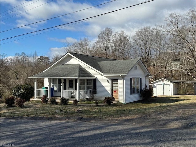 view of front of property with an outbuilding, covered porch, roof with shingles, and a shed