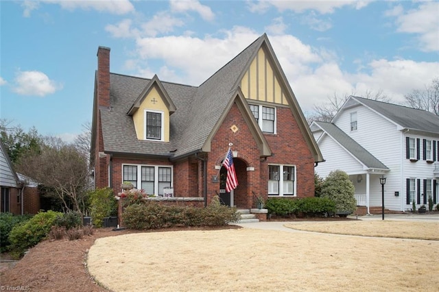 view of front of house featuring a front yard, a shingled roof, a chimney, and brick siding