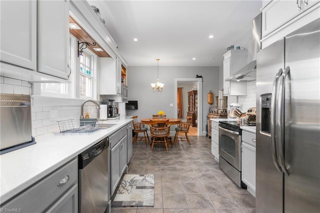 kitchen with a chandelier, a sink, light countertops, appliances with stainless steel finishes, and gray cabinets