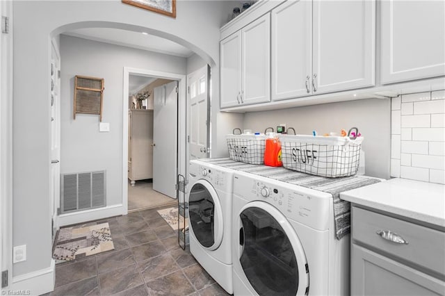 washroom with cabinet space, visible vents, arched walkways, baseboards, and washing machine and dryer