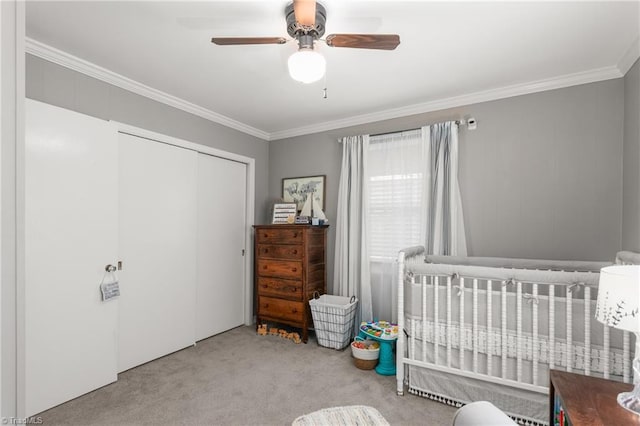 bedroom featuring ornamental molding, a closet, carpet, and a crib