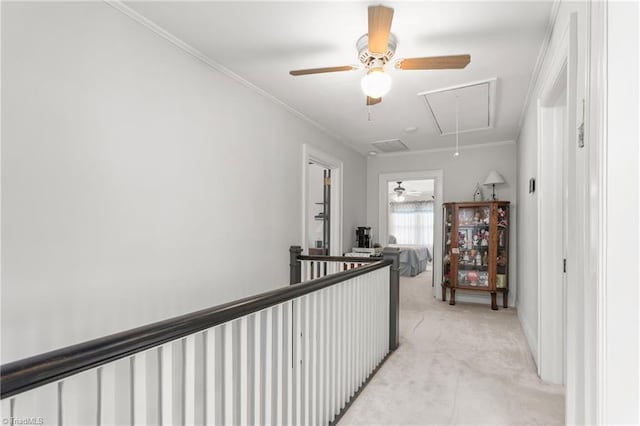 hallway with light carpet, attic access, ornamental molding, and an upstairs landing