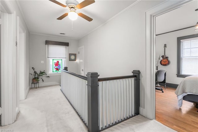 hall with a wealth of natural light, ornamental molding, an upstairs landing, and baseboards