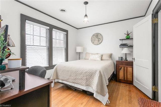 bedroom with ornamental molding, light wood-type flooring, and visible vents