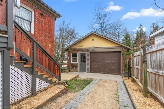 exterior space with driveway, a garage, fence, an outdoor structure, and brick siding