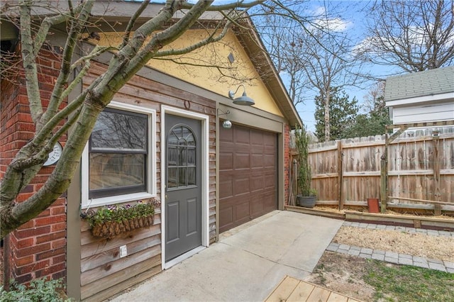 exterior space featuring a garage, driveway, fence, and brick siding