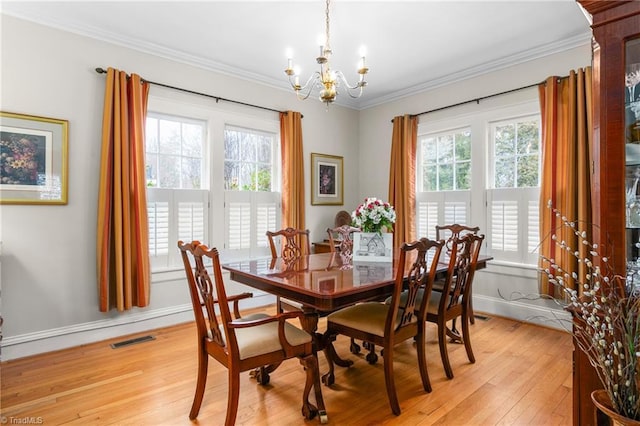 dining room featuring light wood-type flooring, plenty of natural light, visible vents, and crown molding