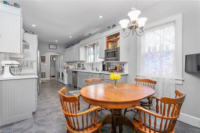 dining area with arched walkways, baseboards, washer / dryer, and an inviting chandelier